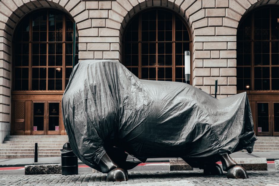 Covered Charging Bull statue on a Wall Street street, symbolizing market uncertainty