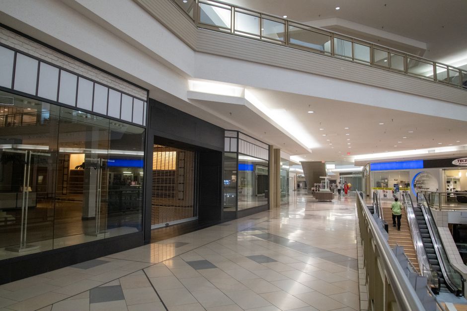 Empty shopping mall interior with closed storefronts and escalator