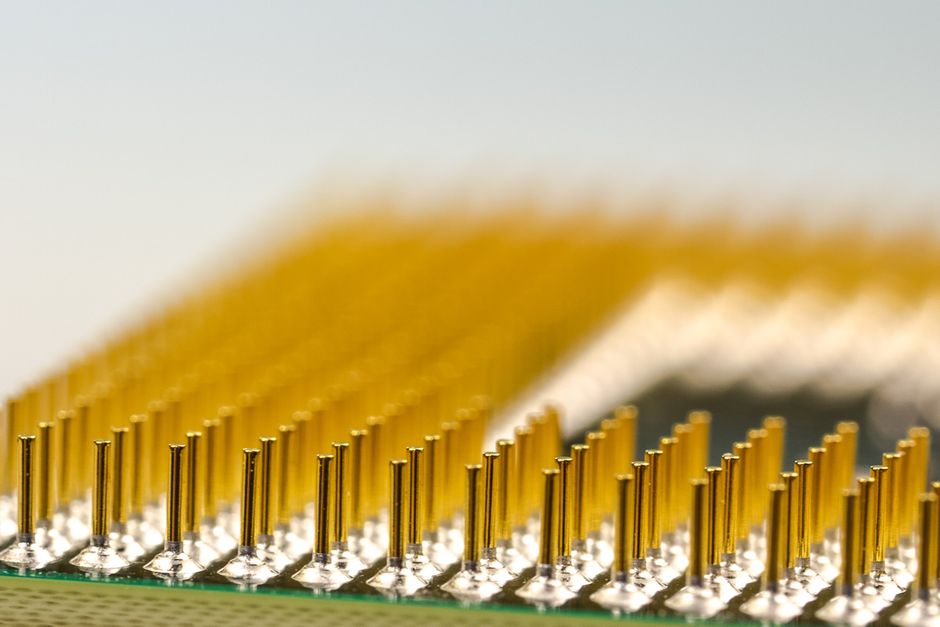 Macro photograph of a CPU microchip showing golden processor pins, representing semiconductor hardware.