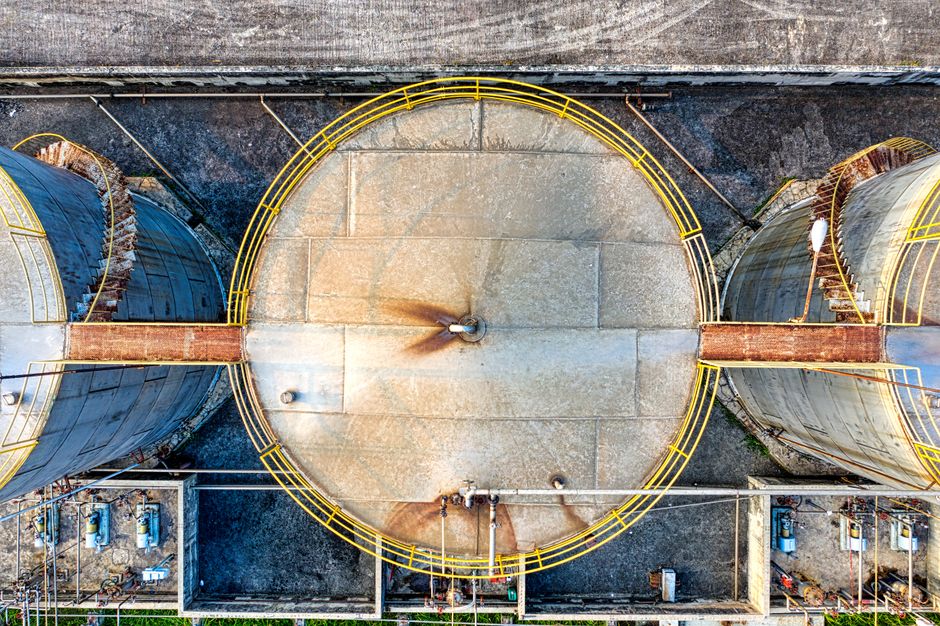 Industrial liquid storage tanks connected by pipelines at a factory complex, viewed from above