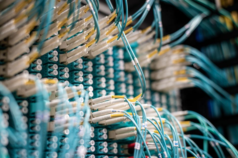 Fiber-optic cables and connectors in a cloud-computing infrastructure environment representing the AI investment cycle.
