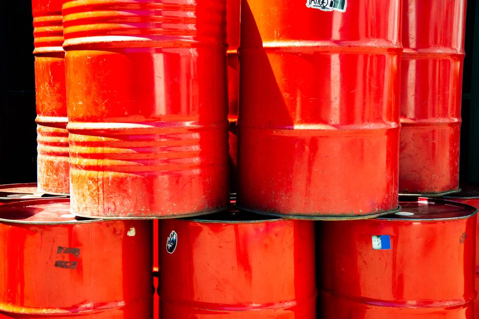 Stacked red industrial oil barrels in daylight