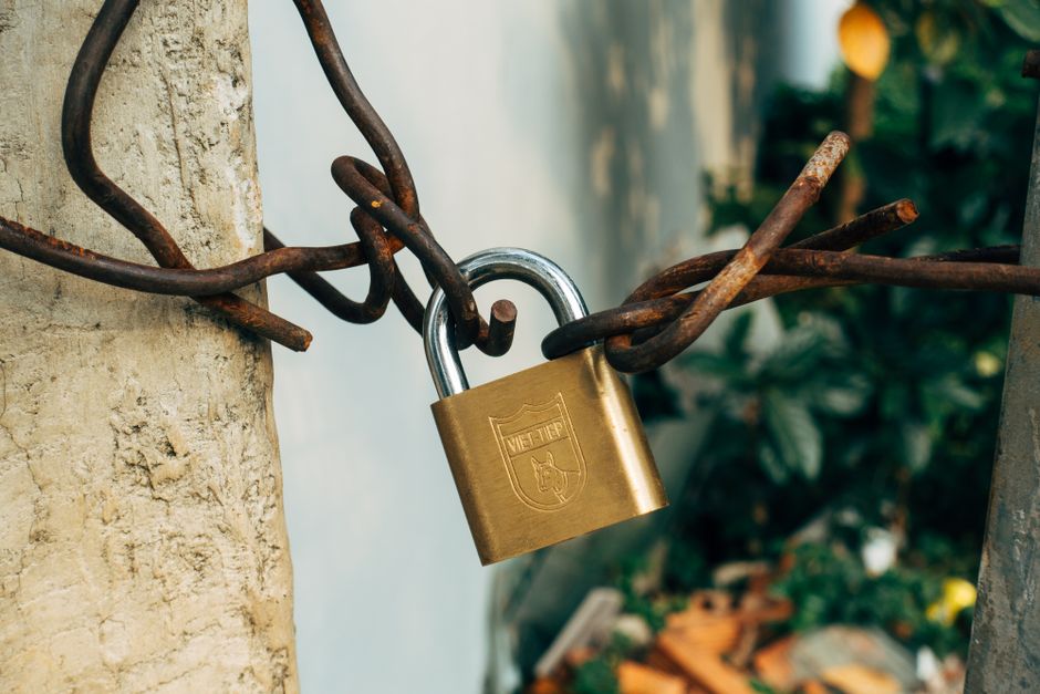 A brass padlock securing a wire on a concrete post, symbolizing locked-up shares.