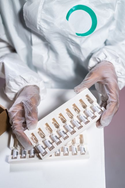 Gloved hands holding pharmaceutical vials in a laboratory setting