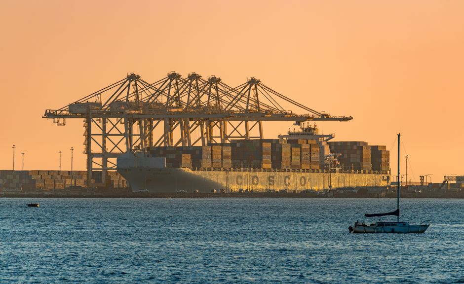 A container ship and port infrastructure represent the global logistics network carrying fuel and consumer goods.