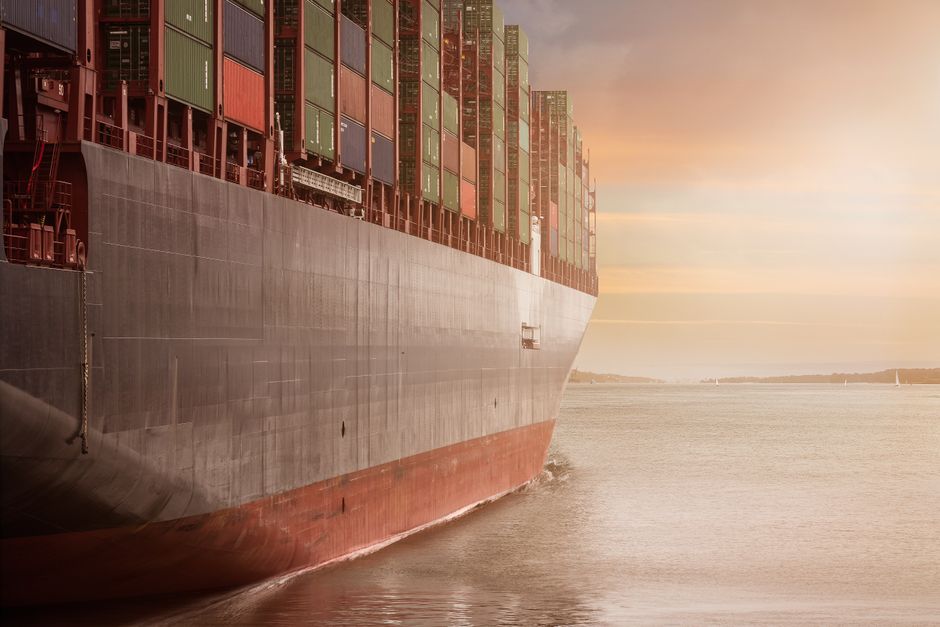 A large container ship navigating on open water at sunset.