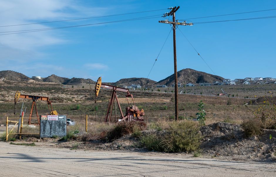 Oil pump jacks operating in a rural landscape with hills in the background