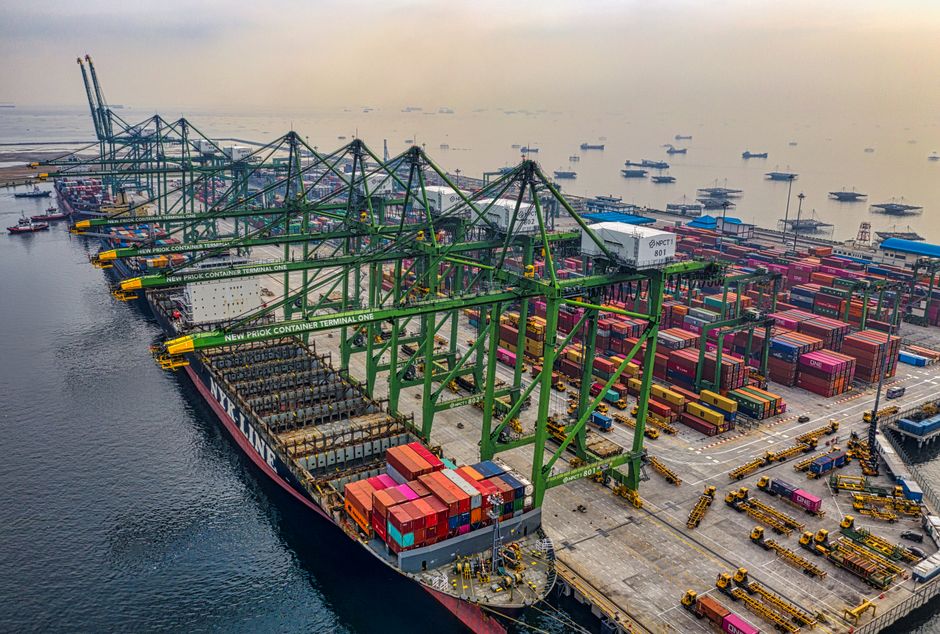 Busy cargo port with cranes and container ships under a hazy sky