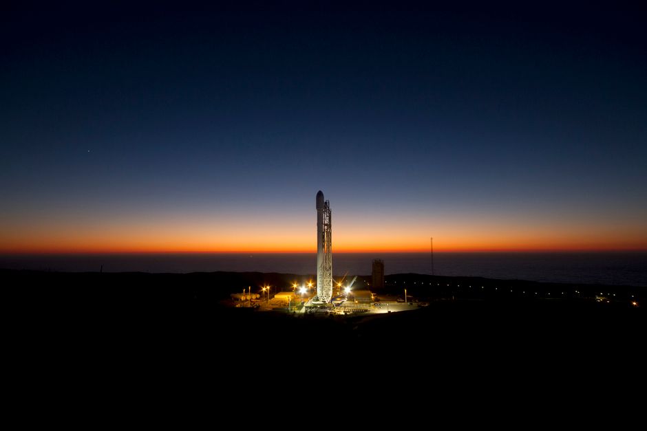 A rocket stands on its launch pad against a twilight sky