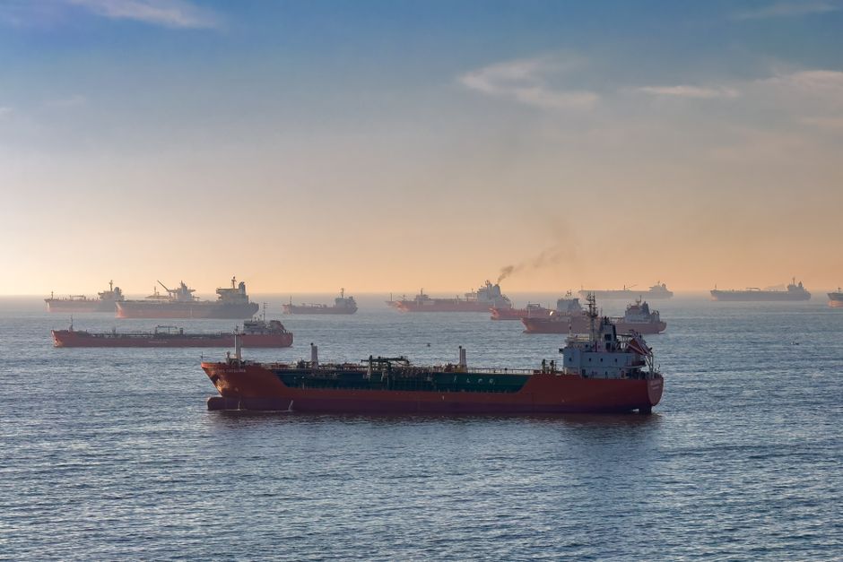 Cargo ships and oil tankers navigate a narrow maritime strait at sunset