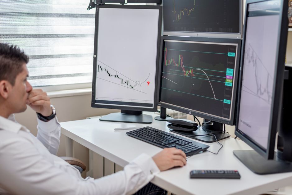 Trading desk with multiple monitors showing financial data