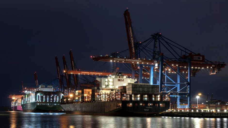 Cargo ships and cranes at an illuminated port as geopolitical tension raises energy and shipping risk
