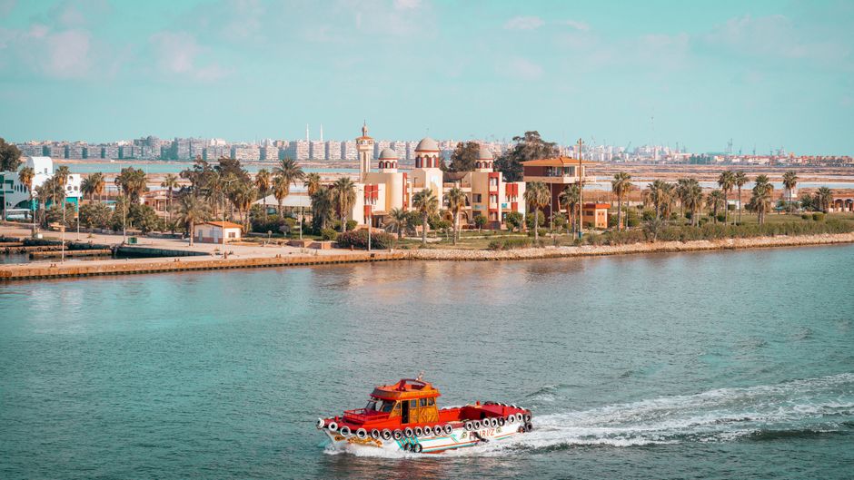 A scenic view of boats cruising near a coastal city with waterfront architecture.