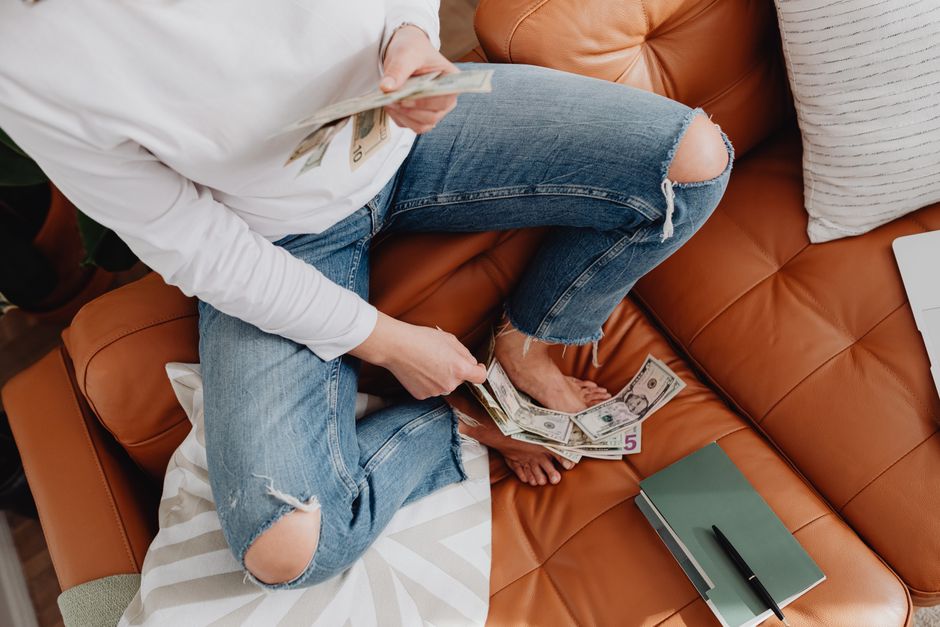 A household budget being counted on a sofa represents the discretionary spending most exposed to confidence and financing conditions.