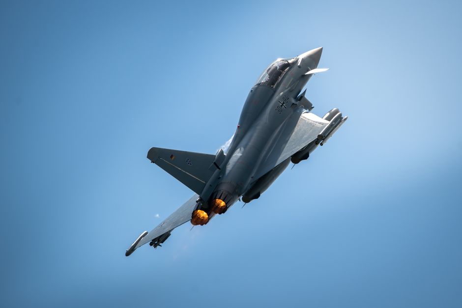 A military fighter jet in flight against a clear blue sky