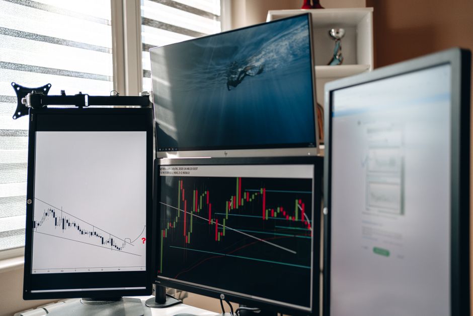 Multiple monitors displaying financial trading charts and data analysis.