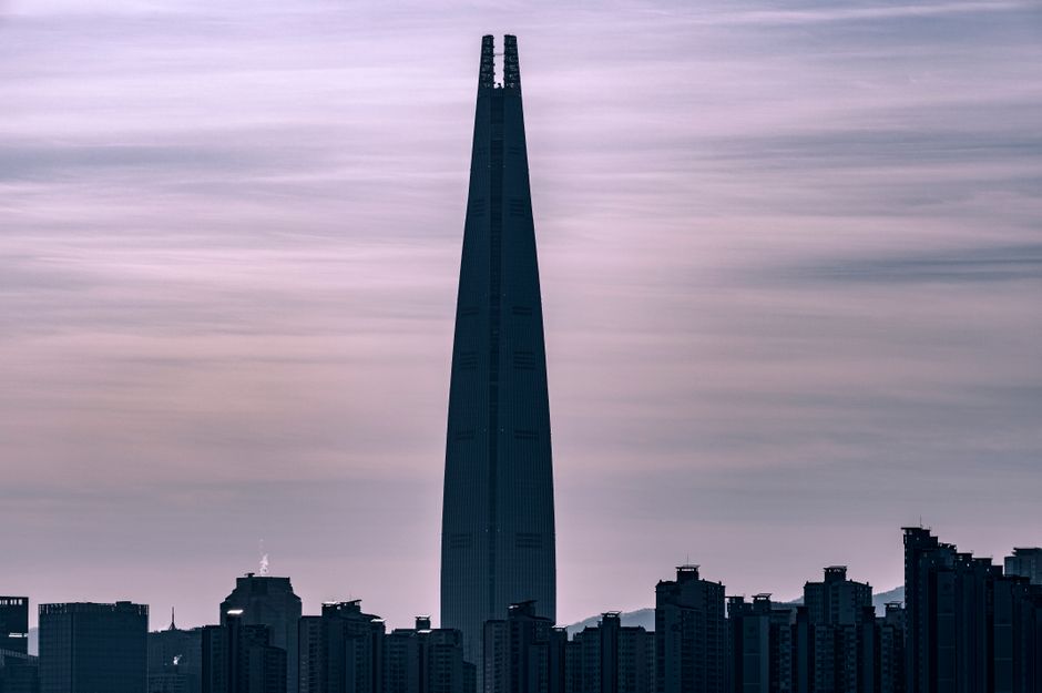 Silhouette of the Lotte World Tower in Seoul against a dusky sky, representing the Korean financial and corporate landscape.
