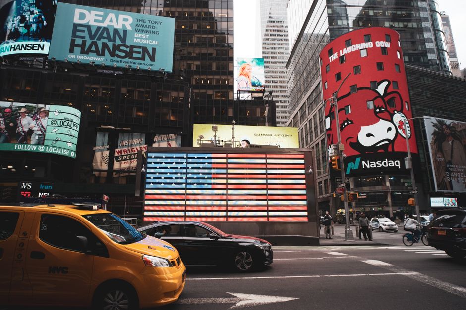 Dynamic view of Times Square with iconic billboards and a yellow taxi in New York City.