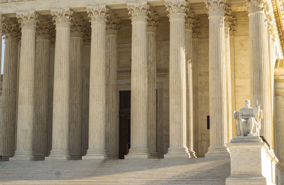 The Supreme Court of the United States facade with iconic marble columns and a statue, captured in natural light.
