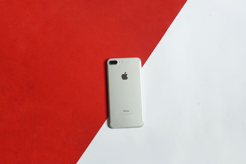 A silver smartphone placed on a contrasting red and white background captured from above.