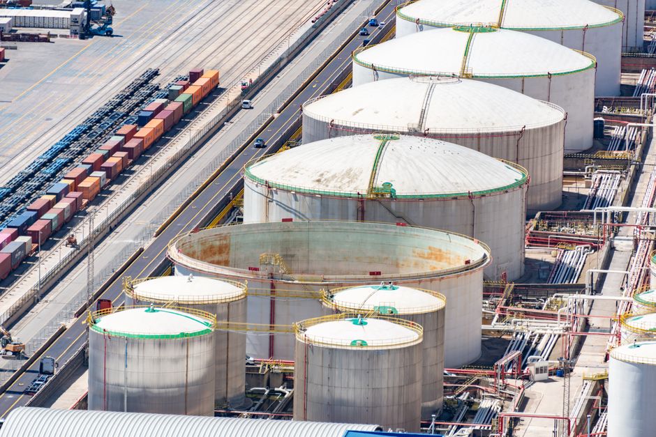 Aerial view of large oil storage tanks in an industrial district with adjacent railway tracks