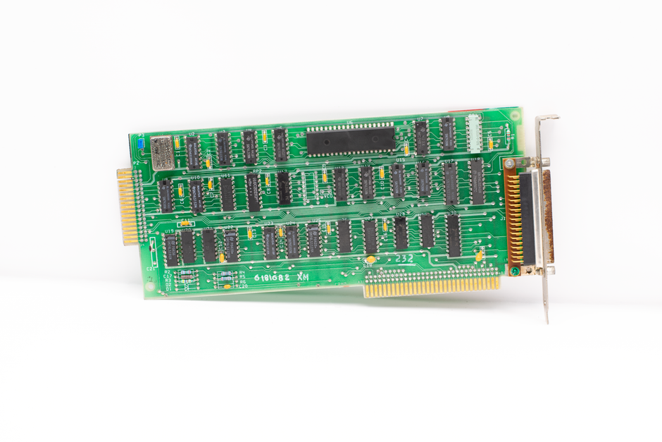Close-up of a vintage computer circuit board with chips and connectors on a white background, representing semiconductor memory technology.
