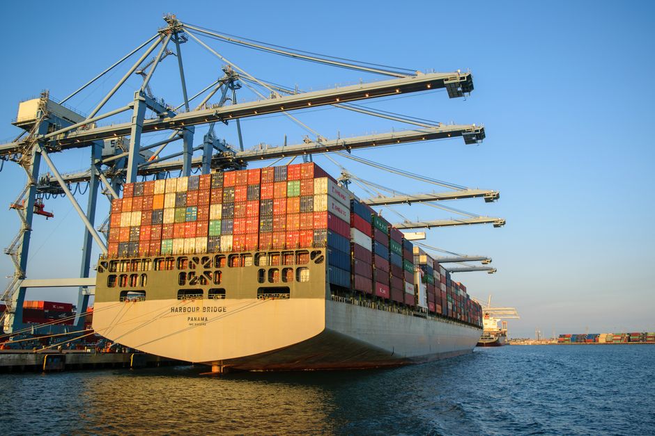 Container ship at an industrial port with loading cranes