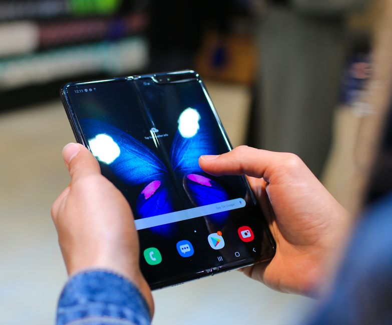 Hands holding a foldable smartphone displaying a colorful screen