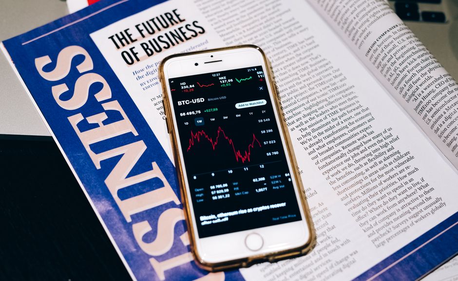 A smartphone displaying a market chart beside a business publication.