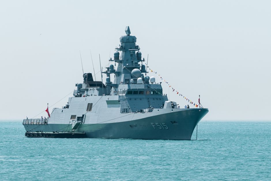 A naval warship sails on calm turquoise waters