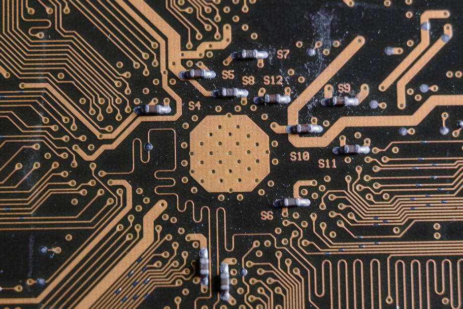 Detailed image of a printed circuit board highlighting electronic pathways and components, representing the semiconductor industry at the center of the AI capex debate.