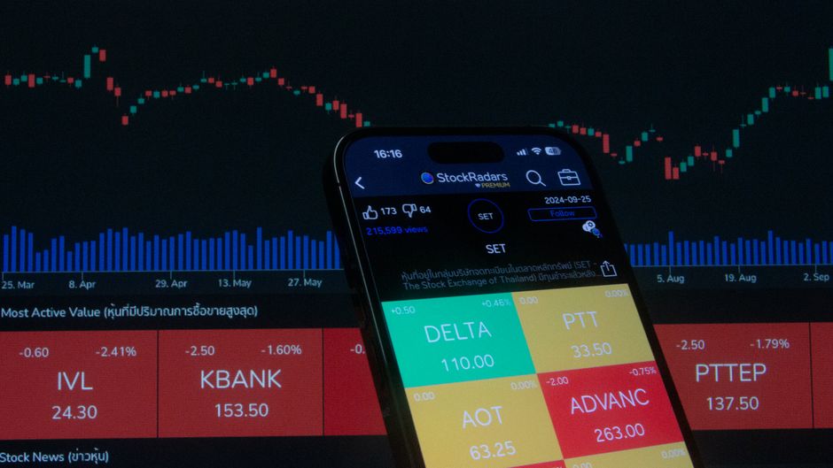A mobile trading screen displays market graphs and price data as equity issuance and liquidity conditions shift.