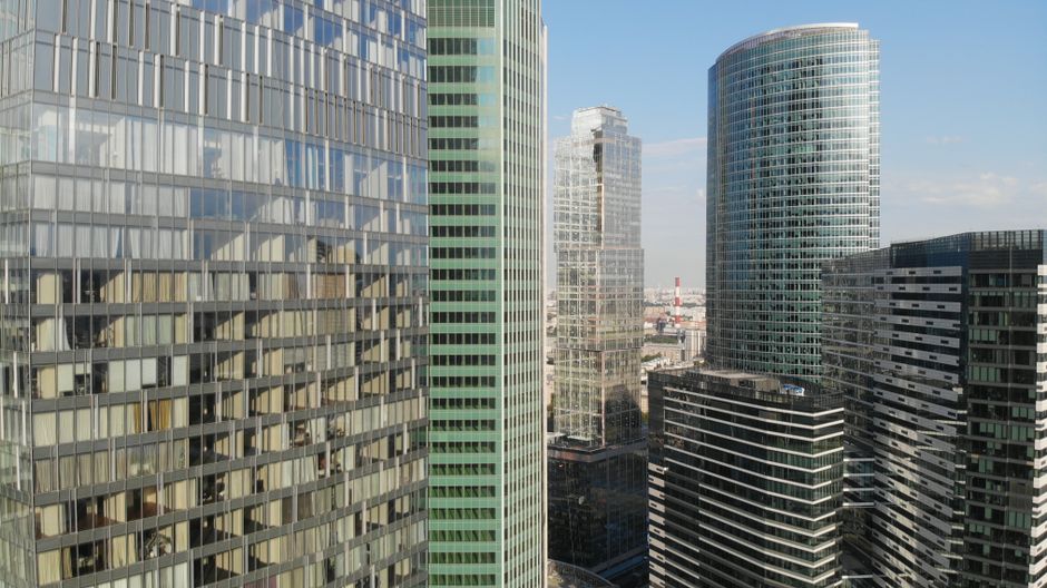 Contemporary glass-sheathed skyscrapers rising against a clear sky, symbolizing the corporate financial district where capital is raised.