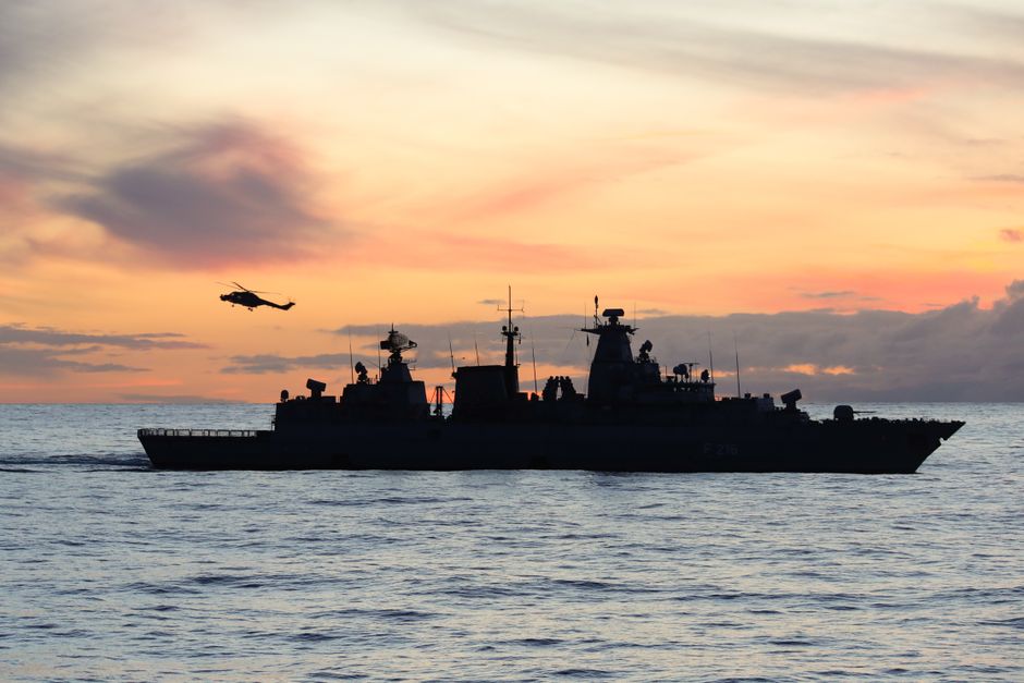Silhouette of a naval warship at sea during sunset