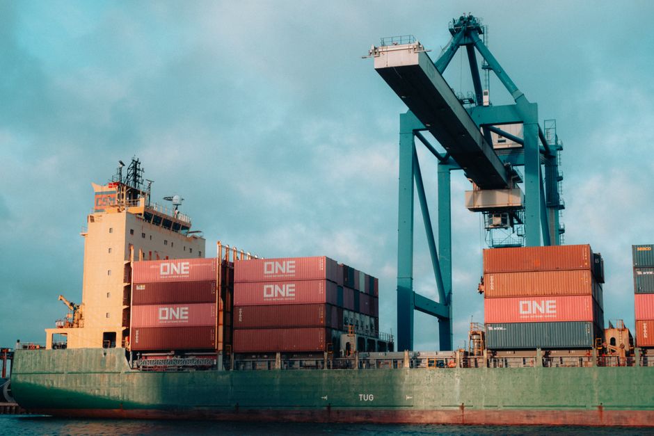 Large cargo ship loaded with colorful shipping containers at a bustling industrial port
