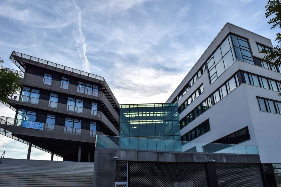 A modern glass-facade corporate office building against a blue sky, representing corporate headquarters and public companies