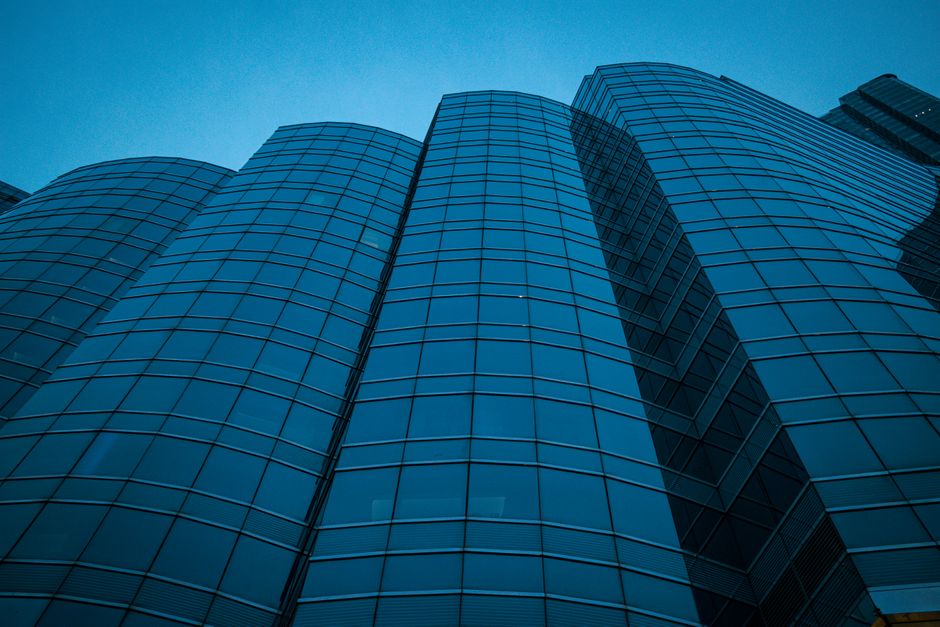 Modern skyscraper facade against a twilight sky, symbolizing the financial district where global listings are priced