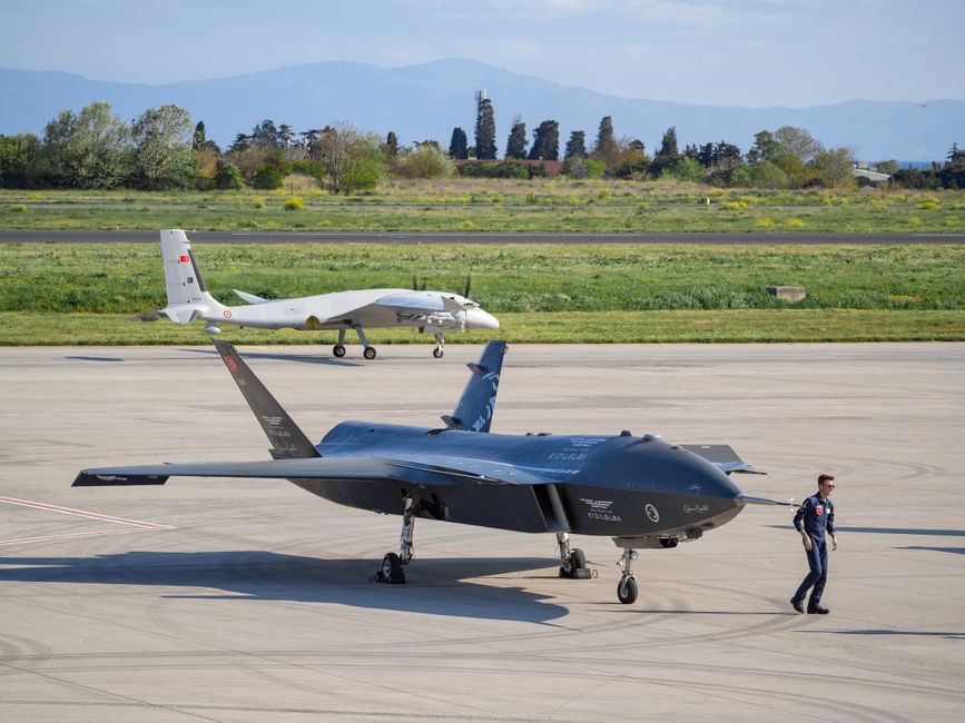 Unmanned aerial vehicles lined up on an airfield tarmac.