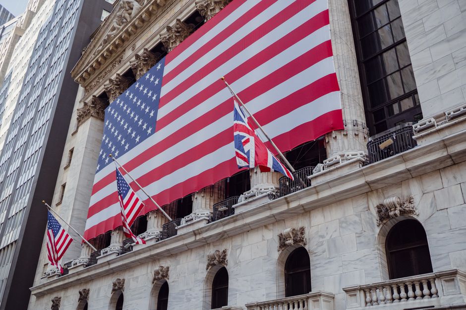 American flag on a historic building exterior with columns, viewed from below against the sky.