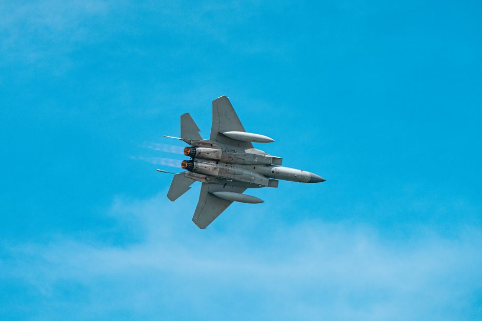 A military jet aircraft flying through a clear blue sky.