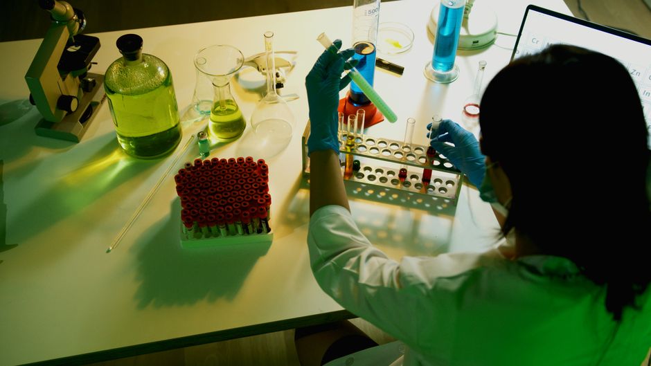 Biotechnology researcher examines vials in a laboratory setting.