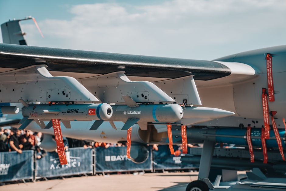 Rows of missiles mounted under the wing of a military fighter jet.