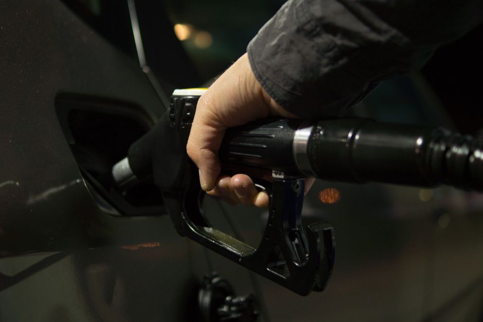 Close-up of a fuel pump nozzle refueling a vehicle at night.