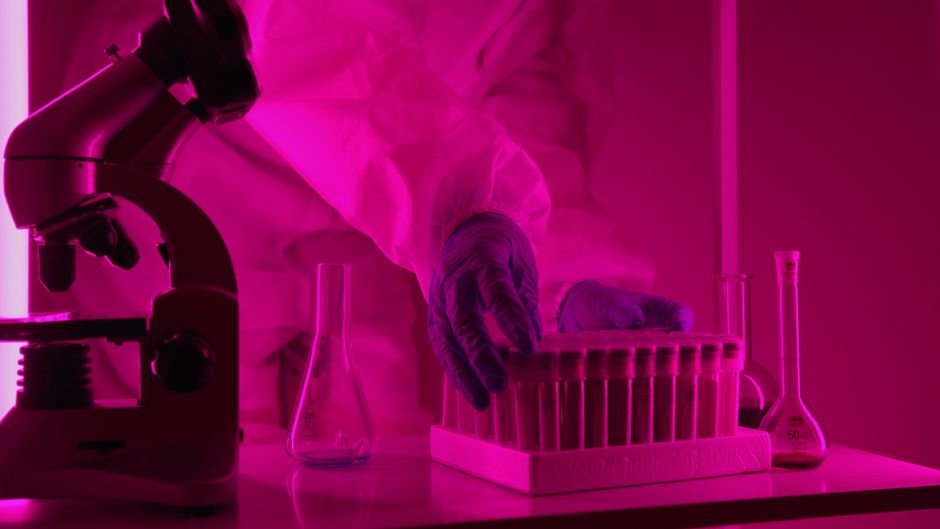 Scientist in protective gloves handling vials in a laboratory setting.