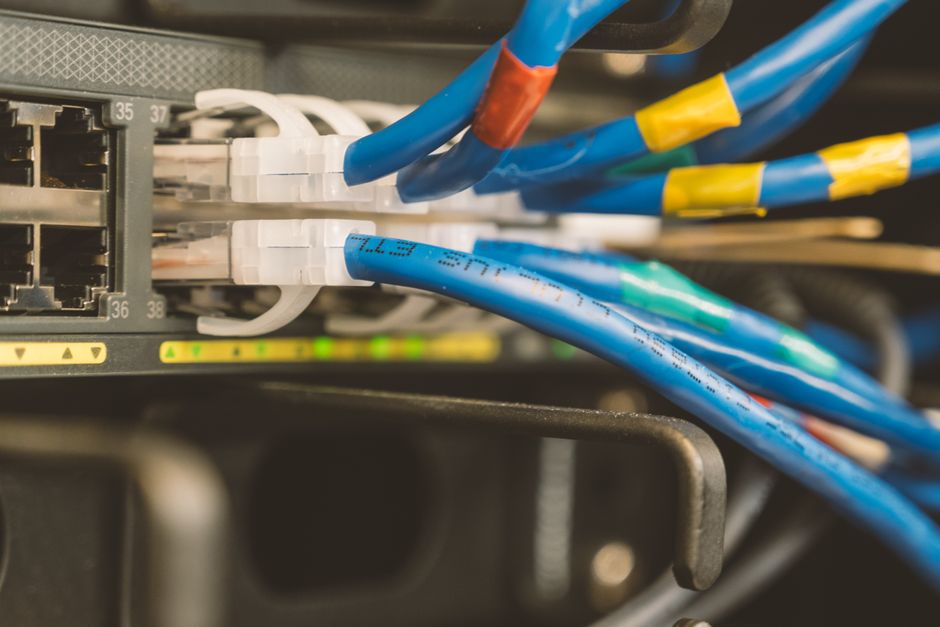 Network switch and blue ethernet cable connected to a system for cloud infrastructure maintenance.