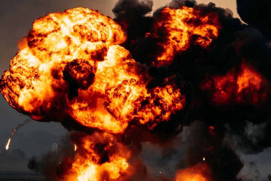 Dramatic explosion with fiery flames and dark smoke billowing skyward