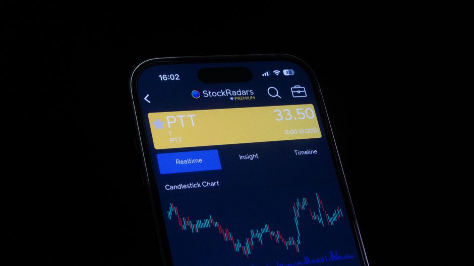 Close-up of a smartphone screen displaying a stock trading app with candlestick charts and real-time market data.