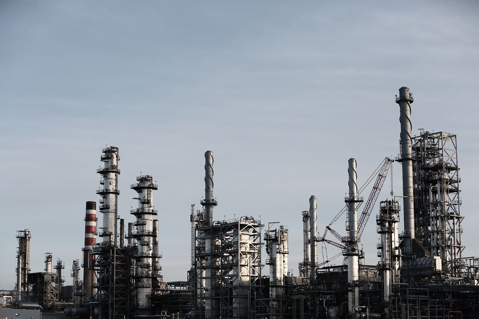 Industrial manufacturing plant with tall chimneys and smokestacks against a clear sky