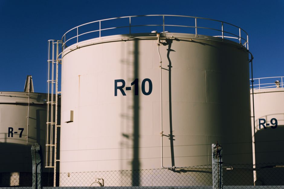 Large industrial oil storage tanks under blue skies, highlighting energy infrastructure and crude supply chains.
